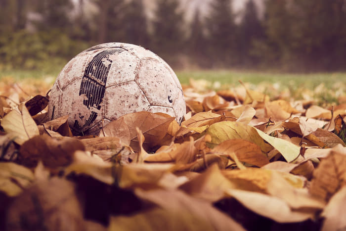 Futballabda focipályán őszi, elszáradt levelek között